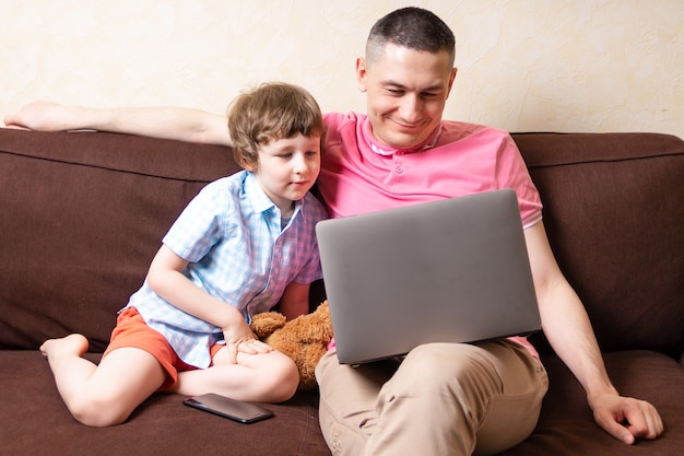 Ojciec i syn z laptopem i telefonem komórkowym w domu