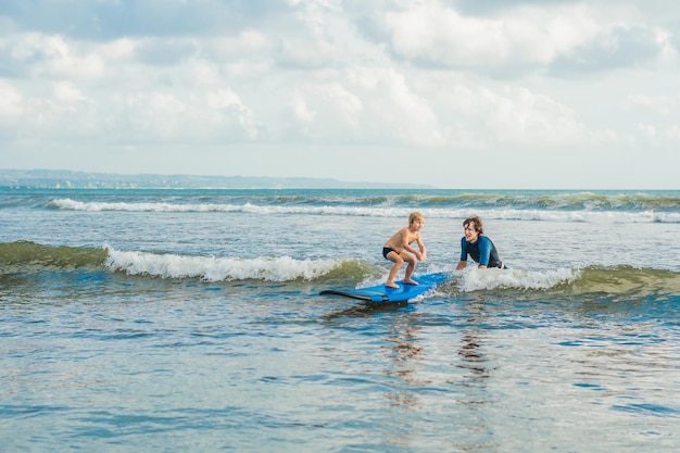 Ojciec Lub Instruktor Uczy Swojego 4-letniego Syna Surfowania W Morzu Na Wakacjach Lub Wakacjach. Podróże I Sport Z Pojęciem Dzieci. Lekcja Surfingu Dla Dzieci