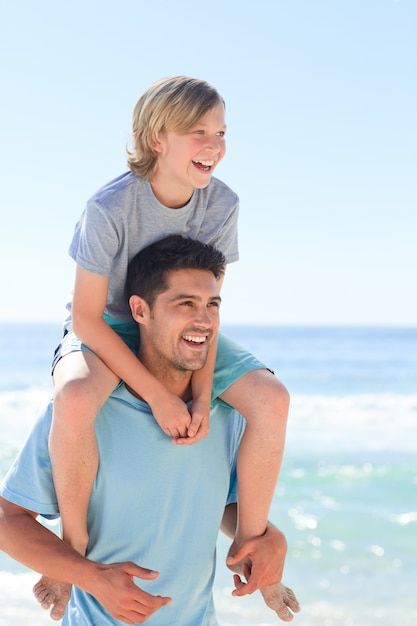 Ojciec ma syna piggyback przy plażą