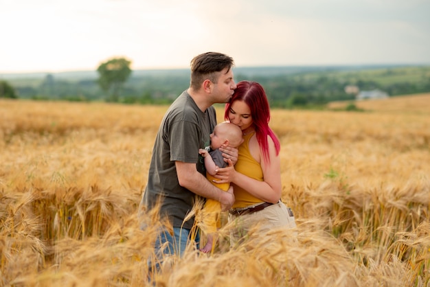 Ojciec, mama i synek bawią się razem na polu pszenicy.