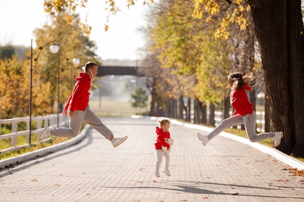 Ojciec, matka i córeczka skaczą w jesiennym parku
