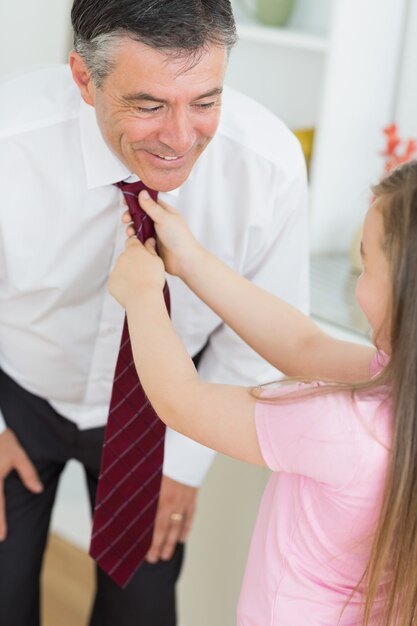 Ojciec nachylając się, aby pozwolić córce naprawić krawat