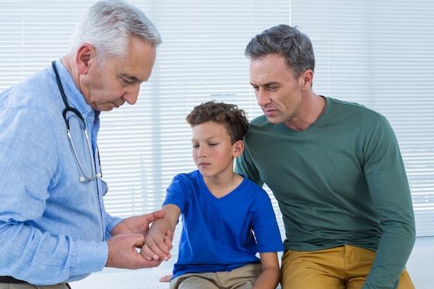 Ojciec patrząc na rękę syna podczas badania przez lekarza