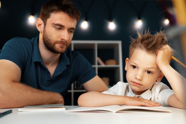 Ojciec pomaga swojemu małemu synowi w odrabianiu lekcji w szkole
