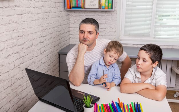 Ojciec pracuje z dziećmi na laptopie w domowym biurze