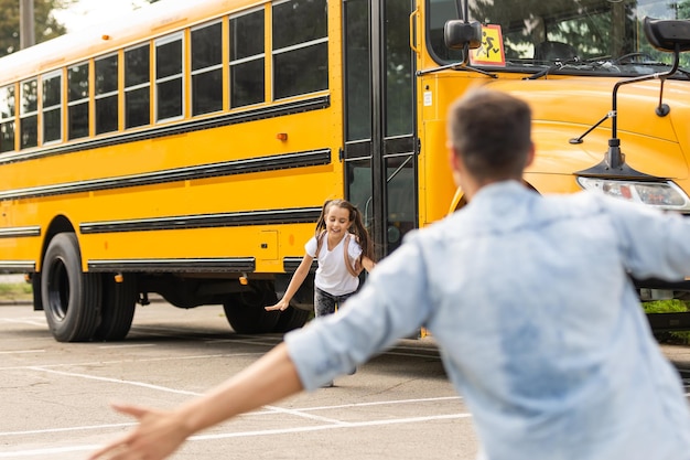 Zdjęcie ojciec spotyka małą córeczkę wychodzącą ze szkolnego autobusu