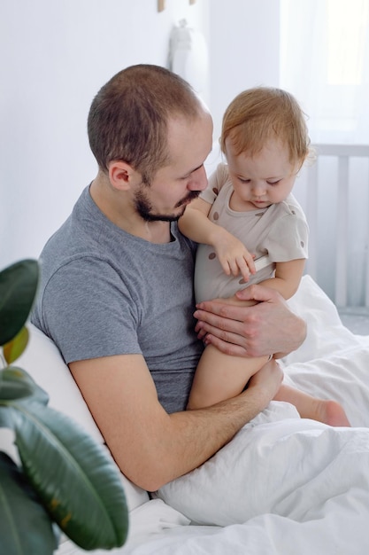 Ojciec trzymający swoje dziecko i patrzący na dziecko mierzące temperaturę za pomocą termometru