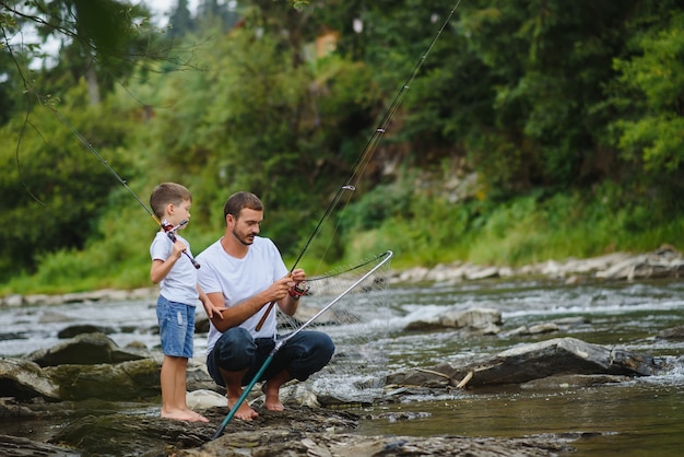 Ojciec uczy syna łowić ryby w rzece
