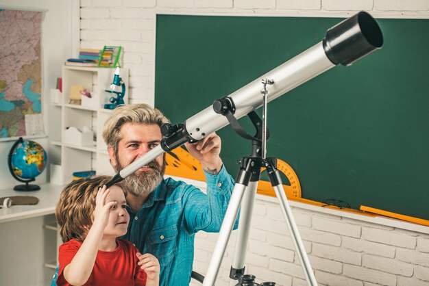 Zdjęcie ojciec uczy syna uczeń ogląda gwiazdy z nauczycielem i trzyma teleskop astronomiczny szkoła podstawowa i edukacja