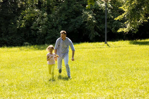 Ojciec z córką bawią się na trawie w parku