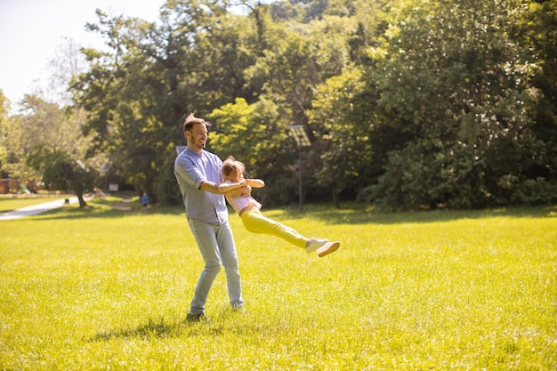 Ojciec z córką bawią się na trawie w parku