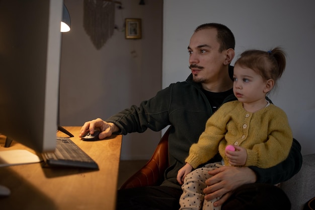 Ojciec z córką korzystający z komputera stacjonarnego w domu