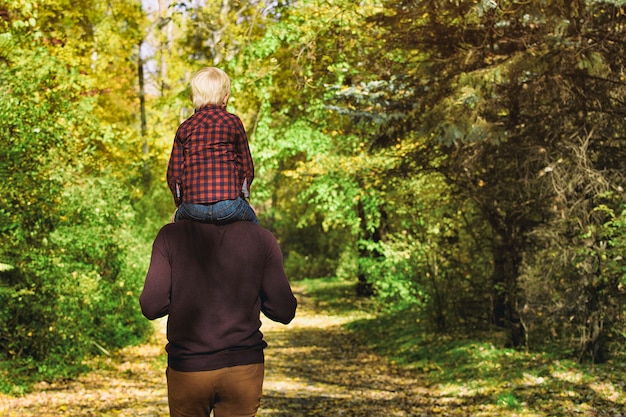 Ojciec z synem na ramionach, spacery w lesie jesienią.