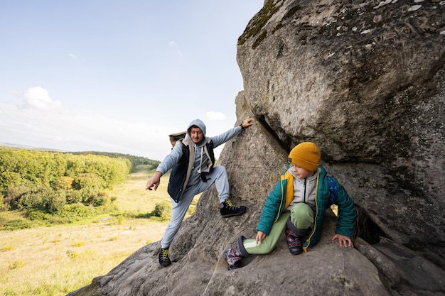 Ojciec z synem wspina się po wielkim kamieniu na wzgórzu Pidkamin na Ukrainie