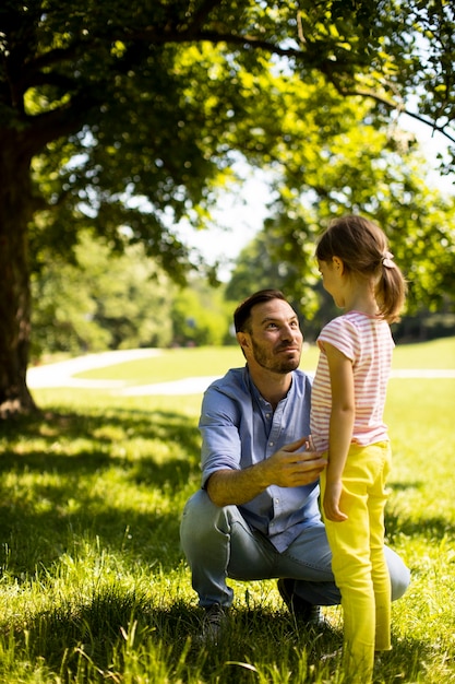 Ojciec z uroczą małą córeczką bawi się na trawie w parku