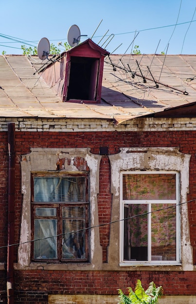 Okna i strych z antenami TV starego murowanego domu fragment elewacji