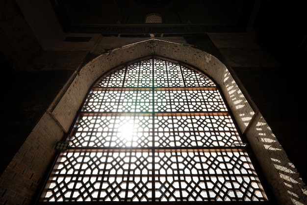 Okno w stylu orientalnym z kratą i wpadającym przez nie słońcem Kratka na oknie Tradycyjny styl islamski w architekturze i wnętrzu Bliskiego Wschodu