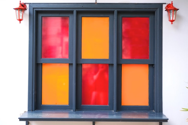Okno z kolorowym szkłem czerwone i pomarańczowe i czerwone światła na ścianie białego domu