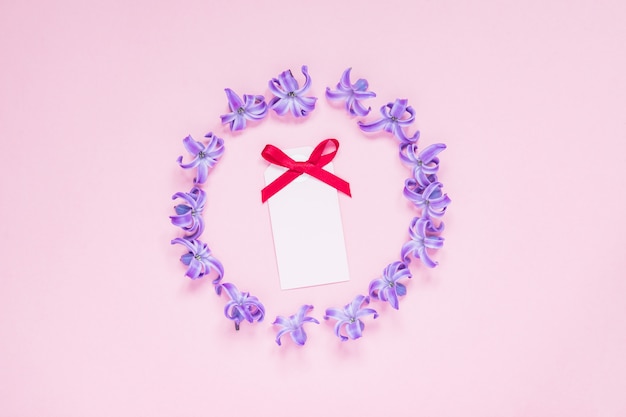 Okrągła Rama Pastelowe Fioletowe Kwiaty Hiacyntu I Pustą Kartkę Z życzeniami Z Czerwoną Kokardą Na Gradientowym Różowym Tle
