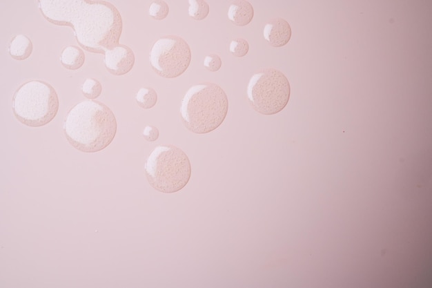 Okrągłe krople przezroczystego serum żelowego na pastelowo różowej syrface z miejscem na kopię Tekstura produktu kosmetycznego do pielęgnacji skóry