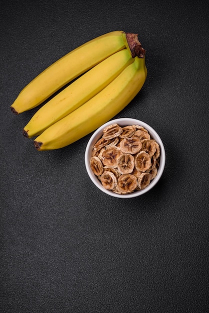 Okrągłe plasterki słodkiego banana na ciemnym betonowym tle Składniki do robienia wegańskich słodyczy