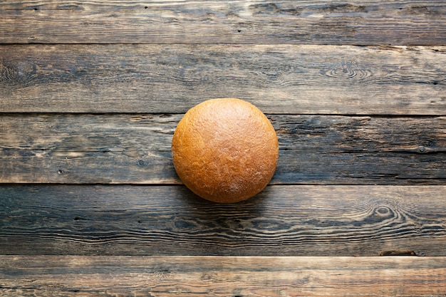 Okrągły bochenek szarego chleba na podłoże drewniane z bliska