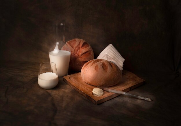 Okrągły chlebek mleczny z masłem i szklanką świeżego mleka