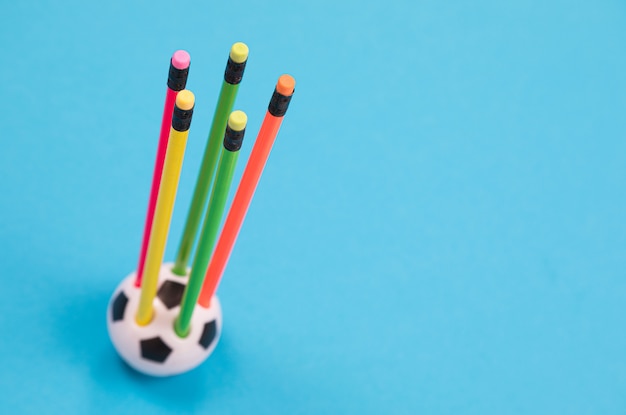 Okrągły kubek w kształcie ołówka z pięcioma kolorowymi ołówkami na lazurowej powierzchni na białym tle