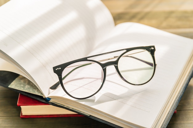 Okulary do czytania założyć na otwartą książkę na drewnianym stole
