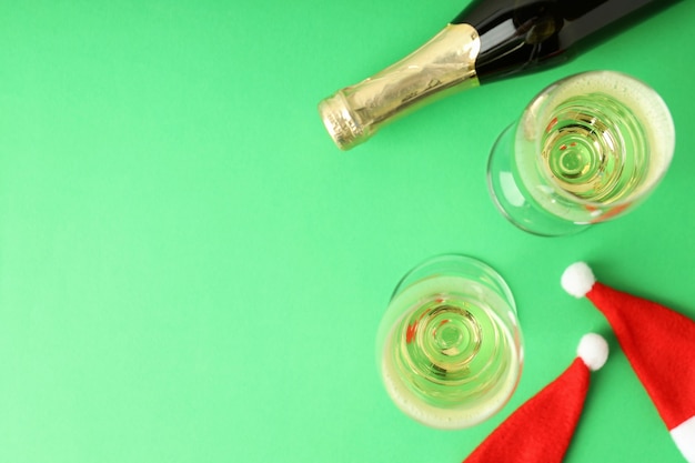 Okulary i butelkę szampana i Santa kapelusze na zielonym tle.
