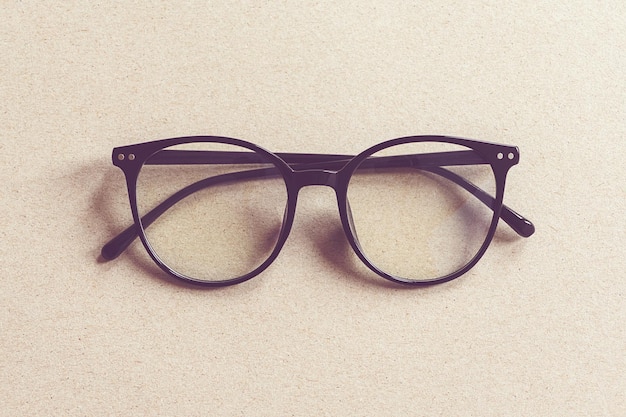 Okulary na beżowym kartonowym tle, minimalistyczne płaskie lay