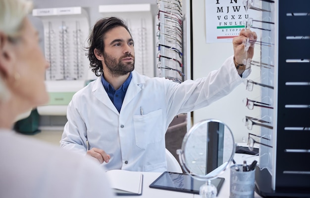 Okulary okulistyczne lub konsultacja kobiety w celu uzyskania porady dotyczącej wzroku u optometrysty lub okulisty z pomocą medyczną Klient rozmawia lub zadaje pytania w celu sprawdzenia zdrowia wzroku u pomocnego optyka