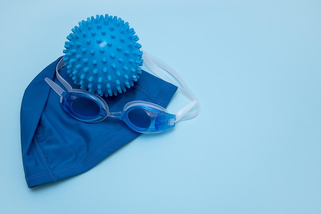 Okulary pływackie i piłka do zabawy w wodzie na niebieskim tle z miejscem na kopię