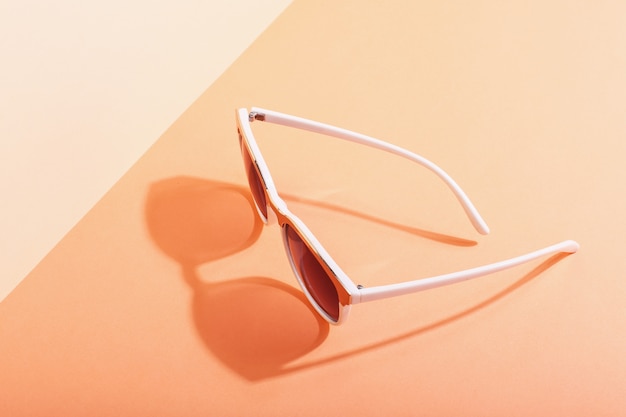 Zdjęcie okulary przeciwsłoneczne leżą na kolorowych rzucających ostry cień, koncepcyjne lato i relaks, minimalizm.