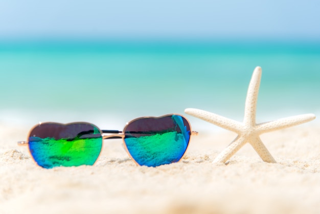 Zdjęcie okulary przeciwsłoneczne moda lato upał kształt na plaży nad morzem pod błękitne niebo. wakacje letni relaksuje tło, kopii przestrzeń.