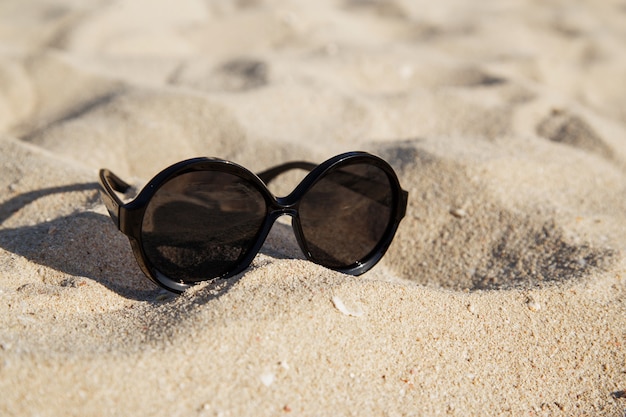 Okulary przeciwsłoneczne na piaszczystej plaży latem.