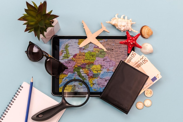 Okulary przeciwsłoneczne samolot paszport tablet pieniądze z mapą muszli rozgwiazdy tło dla podróży banner reklamowy koncepcja podróży