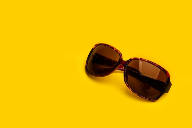 Okulary przeciwsłoneczne z plastikową oprawką na żółtym tle