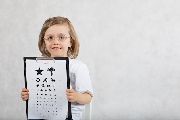 Okulista sprawdza wzrok 5-letniego chłopca za pomocą wykresu oka dla dzieci.