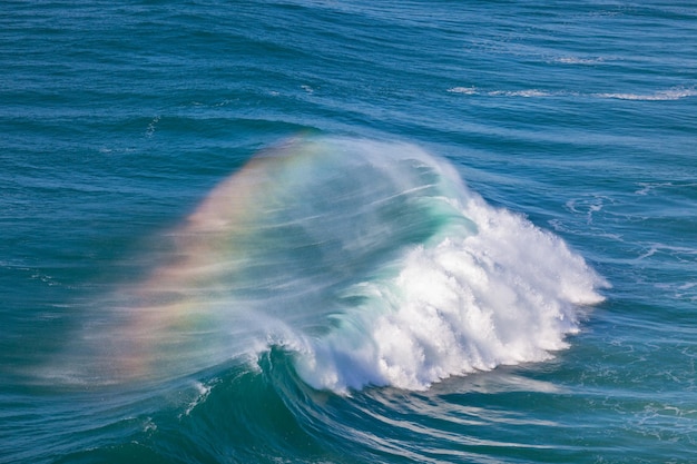 Olbrzymia fala oceaniczna z tęczą w sprayu