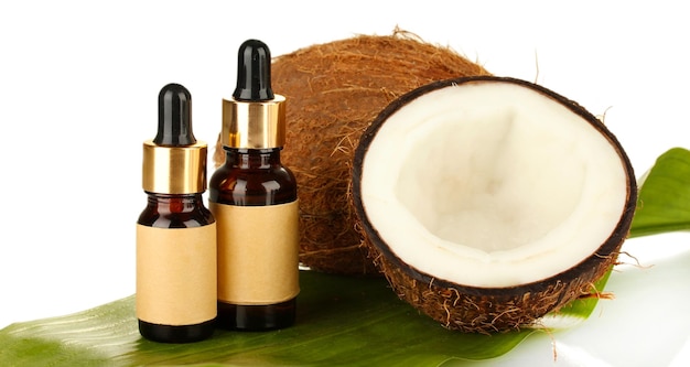 Olej kokosowy w butelkach z orzechami kokosowymi na białym tle