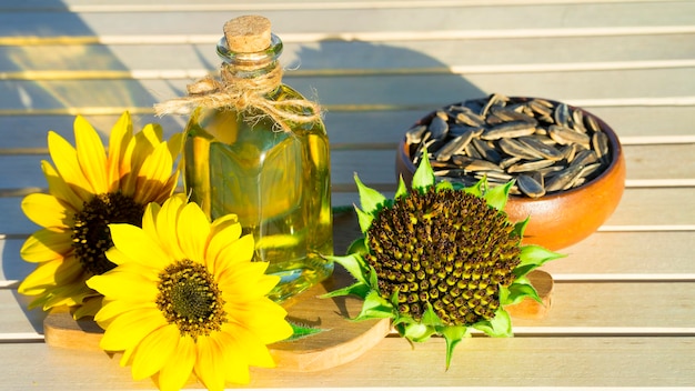 Olej słonecznikowy w butelce, pestki słonecznika i kwiaty słonecznika