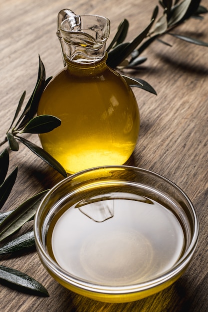 Zdjęcie oliwa z oliwek, liście na drewnianym stole