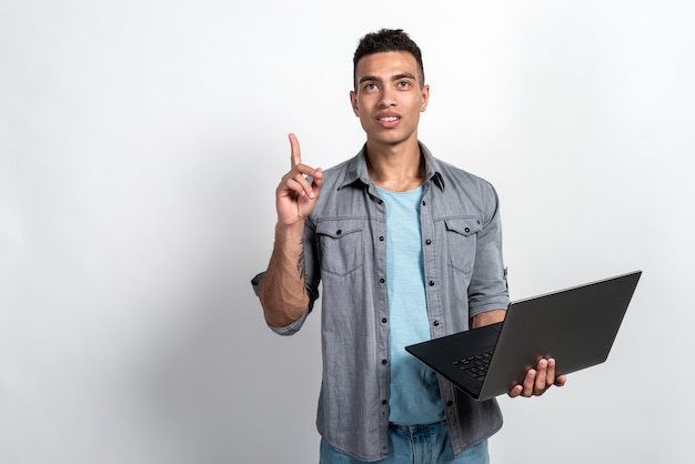 Oliwkowy mężczyzna trzyma laptop w jego rękach stoi