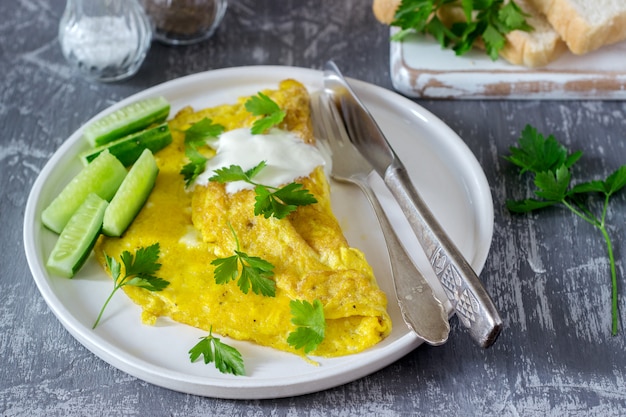 Omlet z natką pietruszki, podawany ze śmietaną i świeżym ogórkiem.