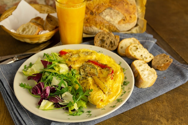Omlet z warzywami i sałatą, pieczywo i sok pomarańczowy, śniadanie
