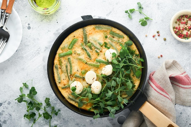 Omlet ze szpinakiem fasolka szparagowa ziemniaki i szpinak zdrowa żywność na czarnej patelni na szarym kamieniu stare rustykalne tło Tradycyjna frittata na śniadanie Tortilla jajeczna Widok z góry płasko leżał Kopiowanie miejsca