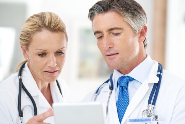 Omówienie diagnozy Ujęcie dwóch lekarzy rozmawiających ze sobą przy cyfrowym tablecie w szpitalu