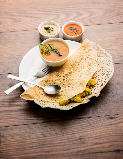 Onion rava masala dosa to południowoindyjskie błyskawiczne śniadanie podawane z chutneyem i sambarem na nastrojowym tle. selektywne skupienie