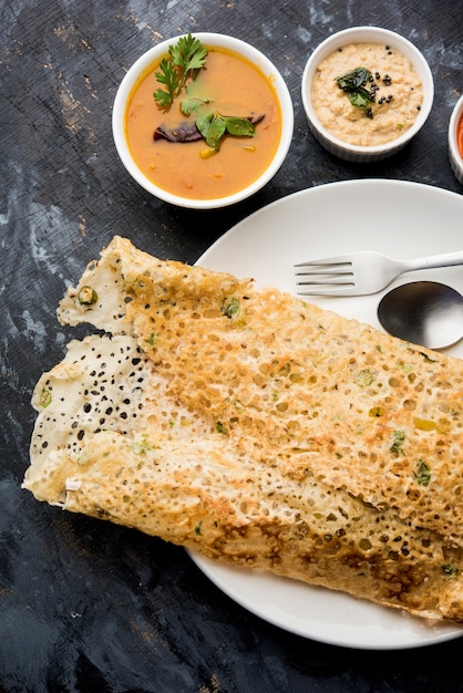 Onion rava masala dosa to południowoindyjskie błyskawiczne śniadanie podawane z chutneyem i sambarem na nastrojowym tle. selektywne skupienie